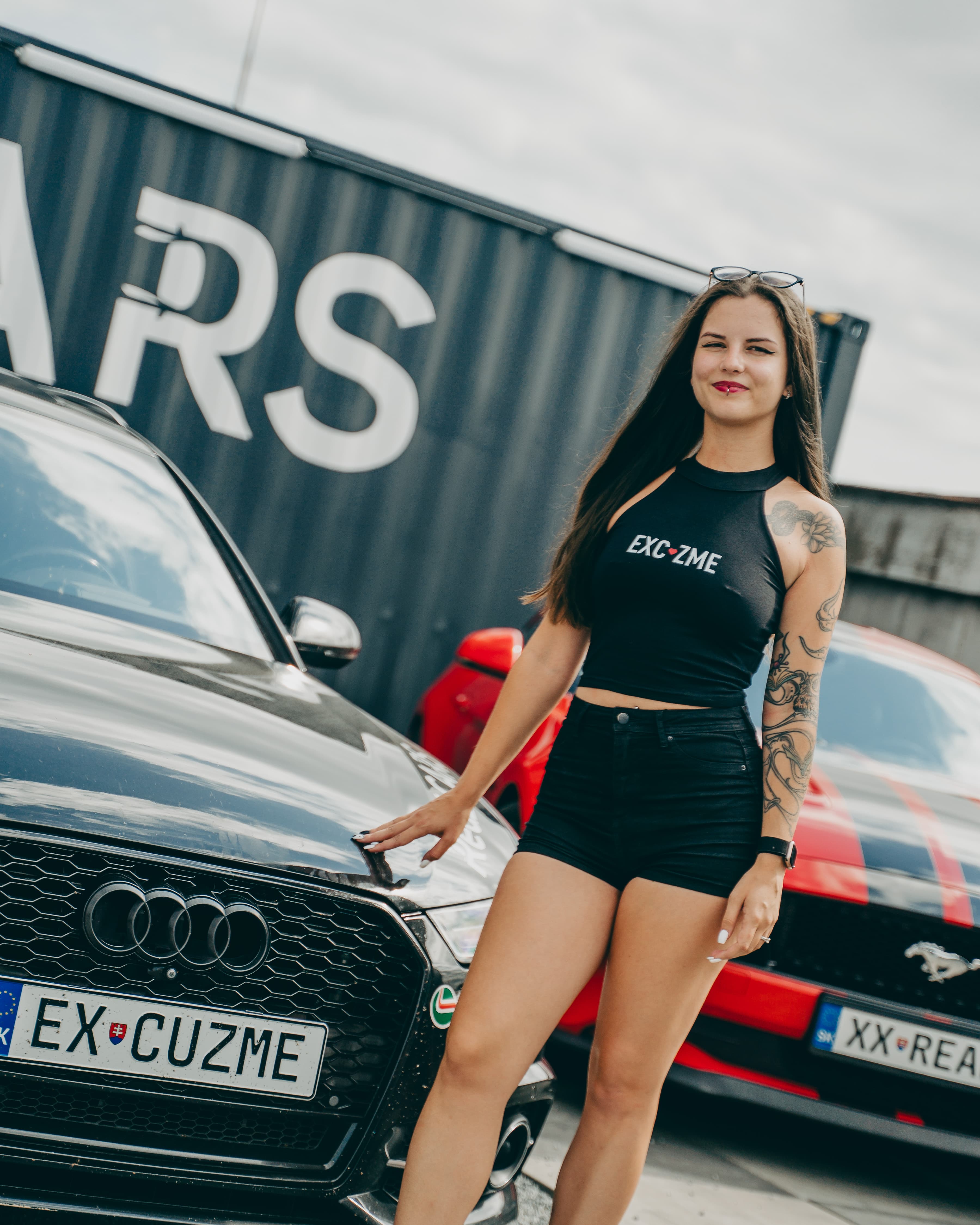 Crop top lookbook záber pred čiernymi a červenými autami.